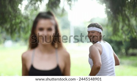 Man looks back to look at beautiful figure girl. Attractive people in sportswear running around park. Man likes figure slender girl. Guy dreams losing weight and having beautiful body. Royalty-Free Stock Photo #2445148901