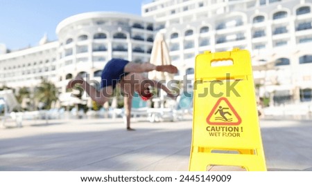 Man falling near yellow plastic sign caution wet floor closeup. Warning signs and signs concept