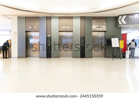 Three passenger Elevators and signboard in lobby of modern building, passengers walking on corridor