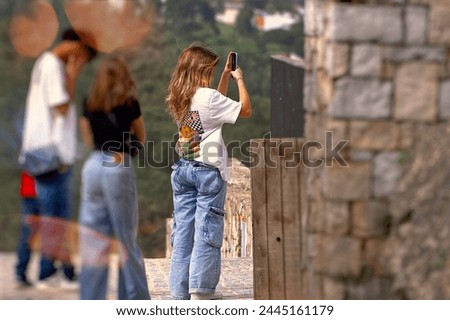 Young girl taking a picture of her friends on the top of the mountain