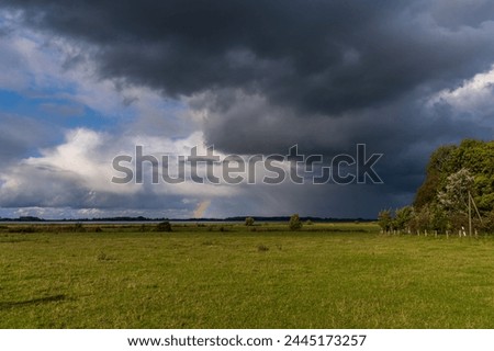 Rainclouds and a rainbow near Boeschow, Mecklenburg-Western Pomerania, Germany Royalty-Free Stock Photo #2445173257