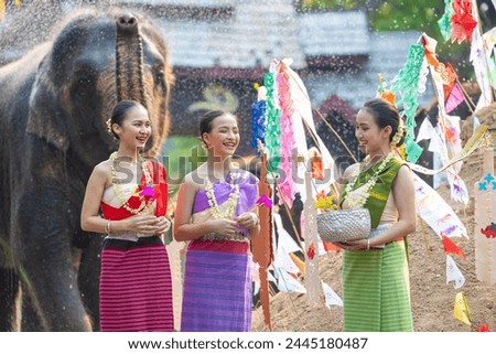 Songkran festival. Northern Thai people in Traditional clothes dressing splashing water together in Songkran day cultural festival with elephant background.