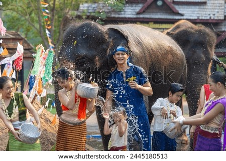 Songkran festival. Northern Thai people in Traditional clothes dressing splashing water together in Songkran day cultural festival with elephant background. Royalty-Free Stock Photo #2445180513