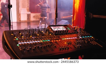 A mixer at a concert to adjust the sound levels of various elements, voices and instruments. Many knobs and sliders on the mixer