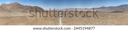 Panoramic drone picture of lonely gravel road through the desert on the edge of the Namib-Naukluft National Park in Namibia during the day