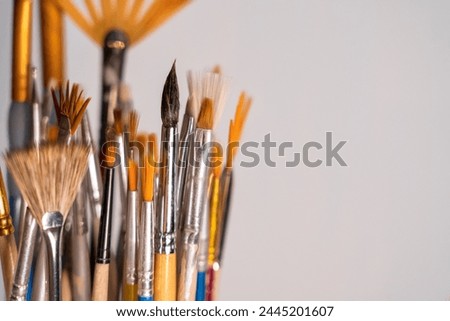 Close-up of several artist's brushes of different types. There is space for an inscription. Form. Gray background. Royalty-Free Stock Photo #2445201607