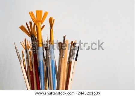 Close-up of several artist's brushes of different types standing on a gray background. Royalty-Free Stock Photo #2445201609