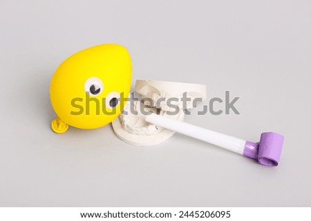 Jaw model and party decor on grey background. April Fool's Day celebration