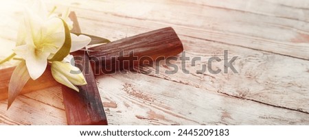 White lily and cross on wooden background with space for text, closeup