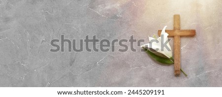 Wooden cross and lily on grey background with space for text, top view