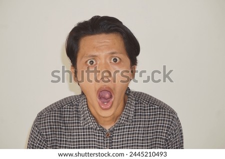 Surprised expression of young Asian man face in black shirt isolated on white background.