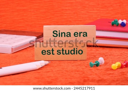 Sina era est studio It means Without anger and addiction on a wooden block next to office supplies