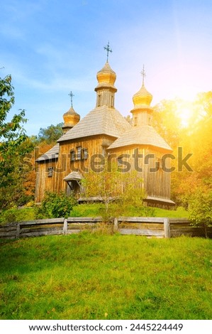 Ancient wooden orthodox church of St. Michael in Pyrohiv (Pirogovo) village near Kiev, Ukraine. There is a bright sun in the blue sky. Royalty-Free Stock Photo #2445224449