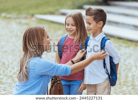 Mother saying goodbye to her little children near school. Mother taking kids to school. Beginning of lessons. First day of fall.