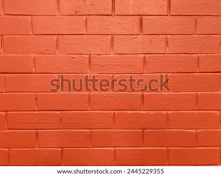 Brightly colored brick wall painted bright orange with a soft lighting gradient creating a wave of color. An organic textured background for graphic design to create a modern, fresh urban style