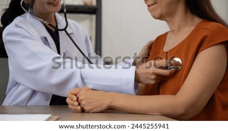 Female doctor and elderly female patient who are undergoing their annual health check-up at the clinic, using a stethoscope to examine patients