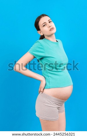 Pregnant woman with a pain in her back on colored Background isolated.
