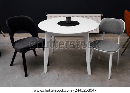 White wooden table combined with black and white wooden chairs with soft fabric upholstery. There is a black and white wax candle on the table