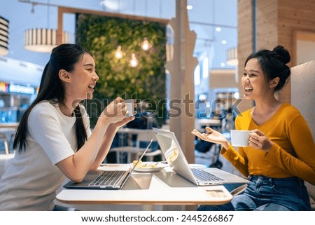 Asian beautiful women having dinner with friend in restaurant together. Attractive young girl feeling happy and relax, having fun talking and eating food at their table in dining room in cafeteria. Royalty-Free Stock Photo #2445266867