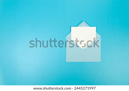 Top view of light blue envelope, white card on blue background. Post flat lay. Copy space.
