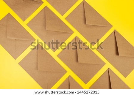 Top view of brown kraft envelopes on yellow background. Post flat lay. Copy space.