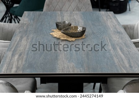 Gray wooden folding table combined with gray chairs with soft fabric upholstery. There is a black porcelain plate on the table