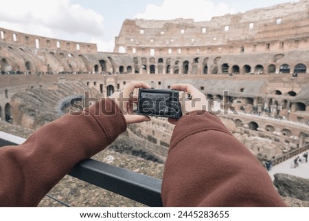 Unrecognizable person taking a photo of the Roman colosseum with a small digital camera