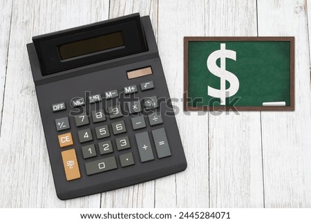  The cost of tuition for education with a black calculator with a chalkboard on weathered wood desk