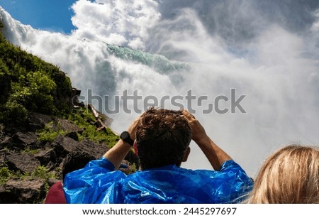 Tourists looking up and taking pictures of American Falls in Niagara Falls New York.