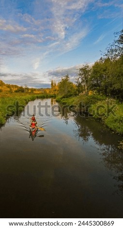 For Canada Day, canoeists in Burnaby, British Columbia, Canada. The kayaker, adorned in a red life jacket, skillfully maneuvers the kayak through the calm waters. Royalty-Free Stock Photo #2445300869