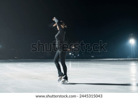 Beautiful young woman ice skating at city ice arena. Winter activities concept