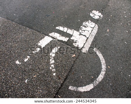 handicapped parking sign painted on asphalt