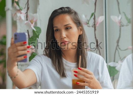 Young brunette woman drinking coffee make selfie by the smartphone . High quality photo