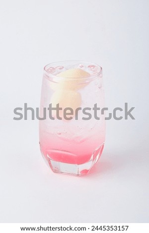 Refreshing Lychee Soda with ice topped with fresh lychee served in a clear glass isolated on white background.