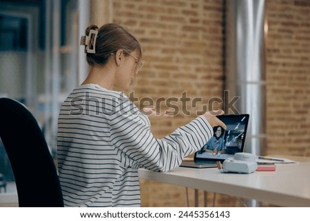 Back view of female manager talking via video call with colleague during meeting in office