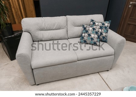 Gray soft sofa in the interior against a black wall