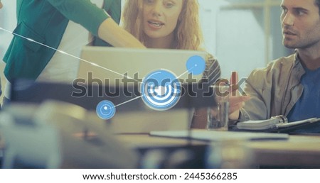 Image of connected icons over diverse coworkers discussing reports on laptop in office. Digital composite, multiple exposure, communication, planning, teamwork and technology concept.
