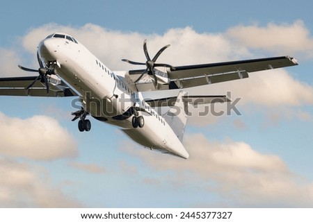 ATR 72 airplane among the clouds. Twin-engine turboprop short-haul regional passenger aircraft. Landing airplane. Cloudy sky.	 Royalty-Free Stock Photo #2445377327