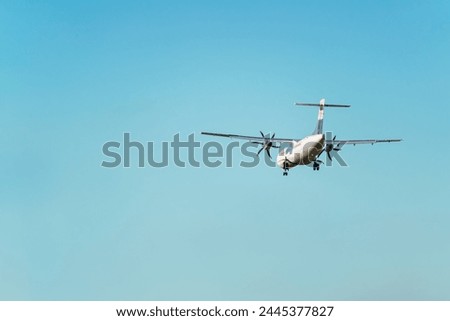Rear view of an ATR 72 airplane, a twin-engine turboprop short-haul regional passenger aircraft. Landing airplane. Blue background. Clear sky. Royalty-Free Stock Photo #2445377827