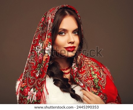 Russian girl Matryoshka style. Fashion woman portrait with traditional red headscarf. Beauty girl model with red lips makeup isolated on studio background. 

