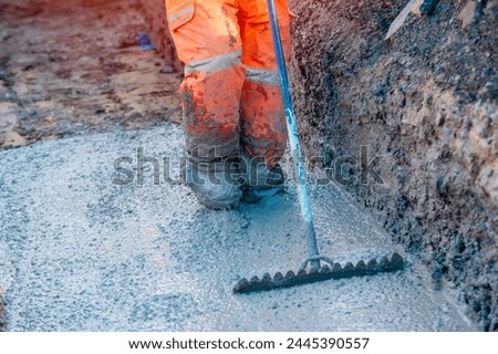 Concrete cast-in-place work. Builder leveling wet concrete. Concrete works on building construction site Royalty-Free Stock Photo #2445390557