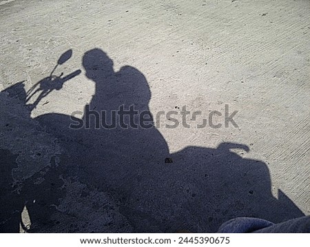 Man stop the motorcycle to take picture of his shadow on the road.