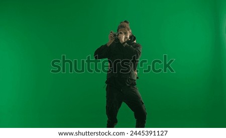 A male traveler takes pictures with a camera while hiking. Man hiker in studio on green screen. Concept of travel, active rest, hiking.