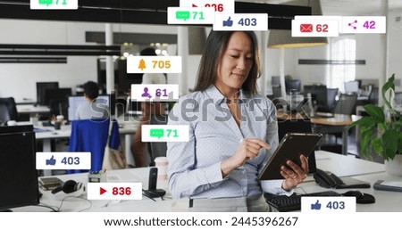 Image of notification bars over smiling asian woman scrolling on digital tablet in office. Digital composite, multiple exposure, business, social media reminder and technology concept.