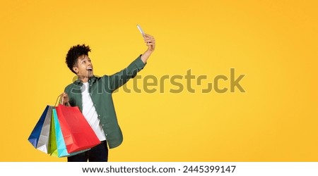 Energetic young black guy capturing a selfie moment with vibrant shopping bags in hand