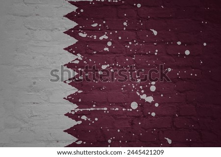 colorful painted big national flag of qatar on a massive old brick wall