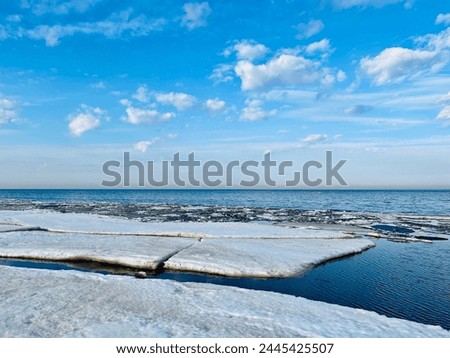 Frozen sea coast, ice at the sea, sea horizon, sky reflection on the water surface, natural colors