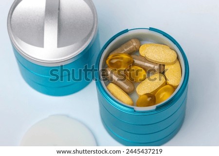 Pills in a pill pot, daily dose of vitamin pills and suppliments in a container. Royalty-Free Stock Photo #2445437219