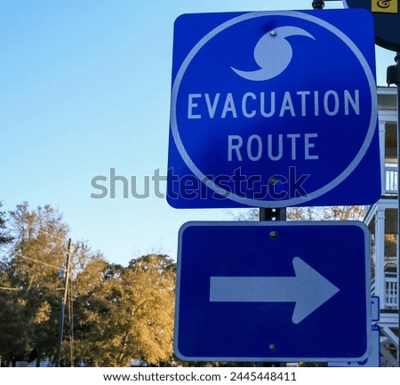 A blue street sign with white text indicating an evacuation route. The sign provides crucial information for directing people to safety in case of emergencies.
