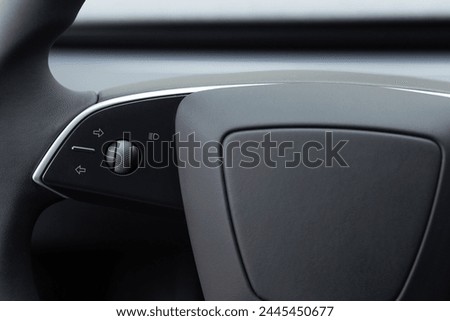 Steering wheel buttons for function control. Expensive car interior with steering wheel. Black steering wheel with multifunction buttons for quick control, close-up in the electric car.